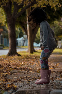 Side view of girl jumping on puddle