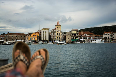 People in front of river with church in background against cloudy sky