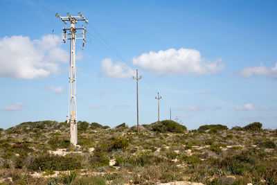 Electricity pylon on field against sky