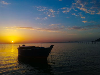 Boat moored on sea against sky during sunset