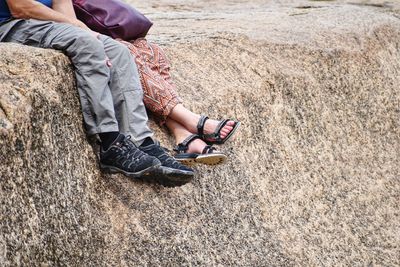 Low section of woman sitting on rock