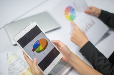 Cropped hands of businesswomen with graphs at desk in office