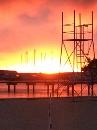 Silhouette sailboats on sea against orange sky