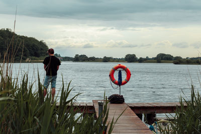 Man standing by lake against sky