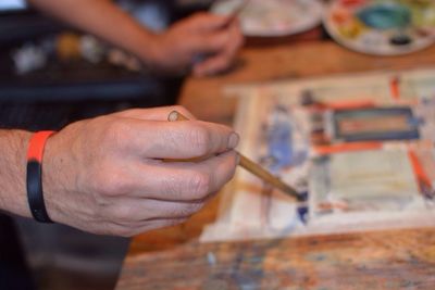 Cropped image of hand holding paintbrush over palette