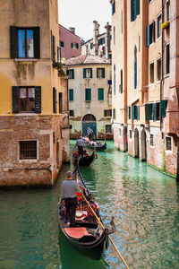 Tourists sailing in a gondola on the beautiful canals of venice in an early spring day