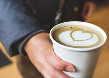 Close-up of hand holding coffee cup on table