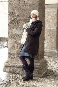 Portrait of woman standing by column during winter