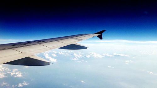 Cropped image of airplane flying over blue sky