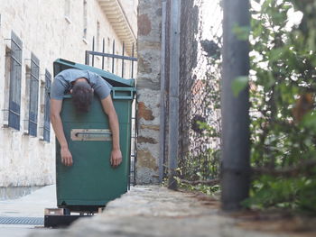Homeless man sleeping in garbage bin