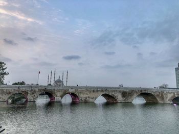 Arch bridge over river against sky