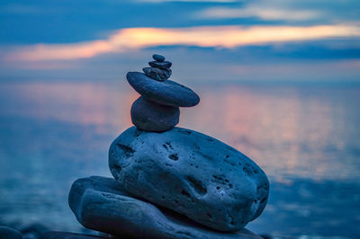 Stack of stones on beach against sky during sunset