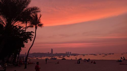 People on beach against sky during sunset