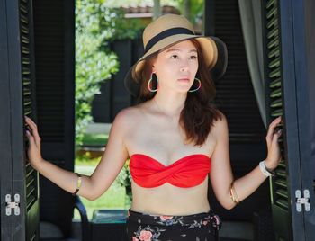 Attractive pretty lady model with hat in swimsuit summer resort opening door accessories bedroom