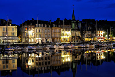 Sailboats moored on illuminated buildings in city at night