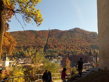 People by trees against sky during autumn