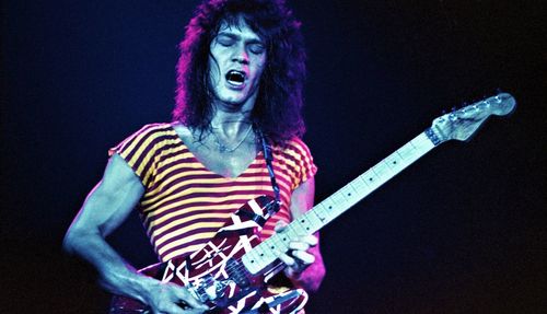 Man playing guitar against black background