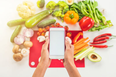 Cropped hands of woman using smart phone against white background