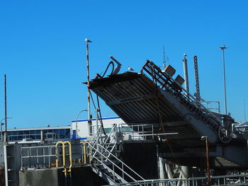 Low angle view of crane against clear blue sky