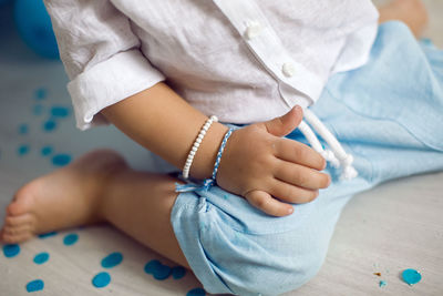 Baby boy in blue pants and shirt standing on the floor next to the cake in blue and white balloons