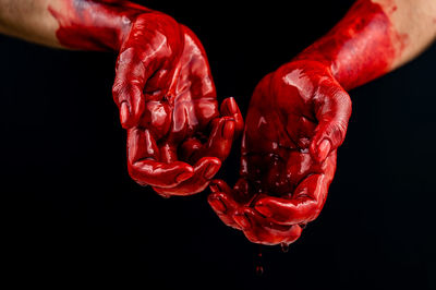 Cropped hand of man with henna tattoo against black background