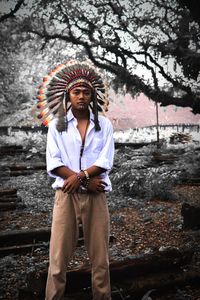 Portrait of man wearing headdress standing in forest