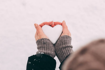 Midsection of woman holding heart shape in winter