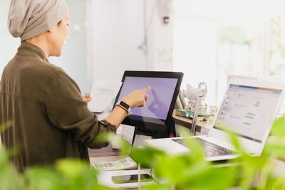 Female cashier operating cash register with order in her hand at restaurant.