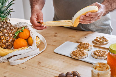 Man preparing healthy organic breakfast with puffed corn cakes, peanut butter and banana.