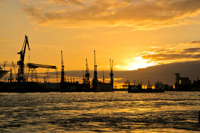 Pier at harbor against sky during sunset