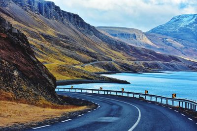 Scenic view of road by mountains against sky