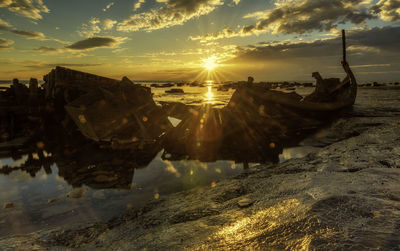 Panoramic view of rocks in sea against sky during sunset