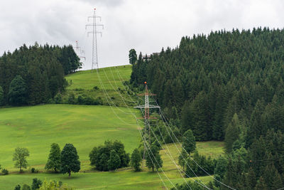 High voltage overhead power line, power pylon, steel lattice tower standing in mountains landscape