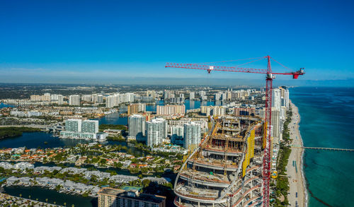 High angle view of buildings by sea against blue sky