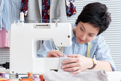 Craftswoman sewing textile on machine at workshop