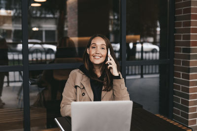 Portrait of a smiling young woman using phone