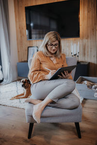 Full length of businesswoman using digital tablet while sitting at home