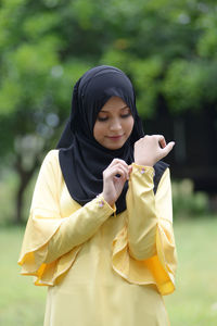 Full length of woman holding yellow while standing outdoors