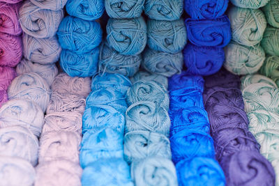 Yarns or balls of wool on shelves in store for knitting and needlework, close up. haberdashery