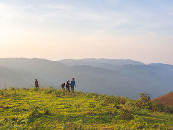 Rear view of man walking on mountain against sky