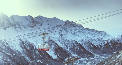 Overhead cable car over snowcapped mountains against sky