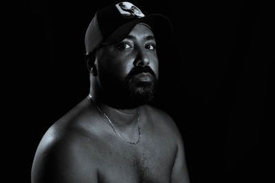 Portrait of young man wearing hat against black background