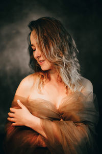 Side view of young woman looking away against black background