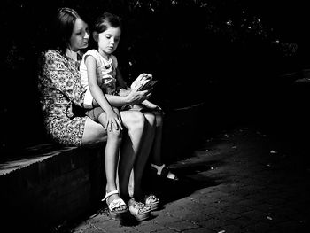 Mother and girl sitting on bench