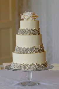 3 tier wedding cake with silver pearls and edible rose topper.