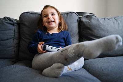 Portrait of smiling boy sitting on sofa at home