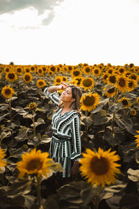 Full length of woman standing on sunflower against sky