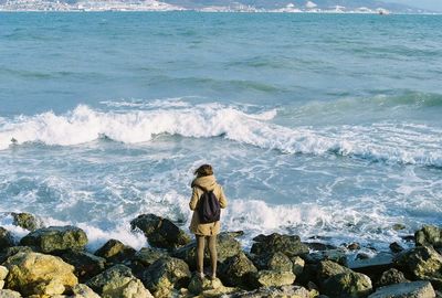 High angle view of people standing on rocks at beach