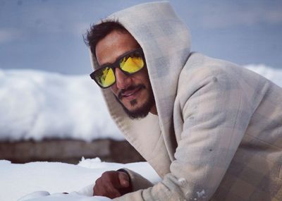 Portrait of man wearing hooded shirt and sunglasses during winter