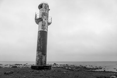 A lighthouse on the shoreline. in the background is the ocean with moody clouds.